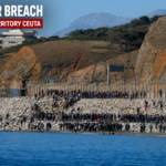 Migrants gather near the border fence in Ceuta after crossing from Morocco into Spanish territory