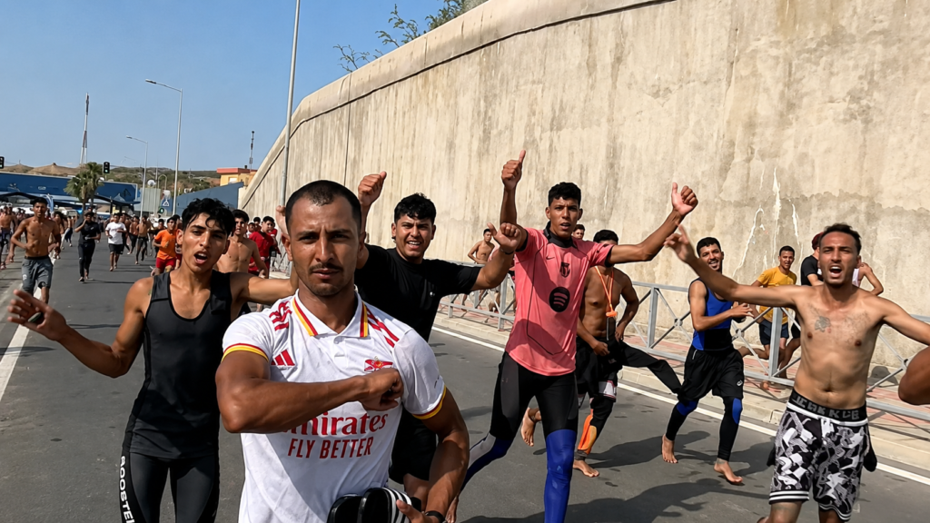 Migrants run along a road in Ceuta after crossing from Morocco into Spanish territory